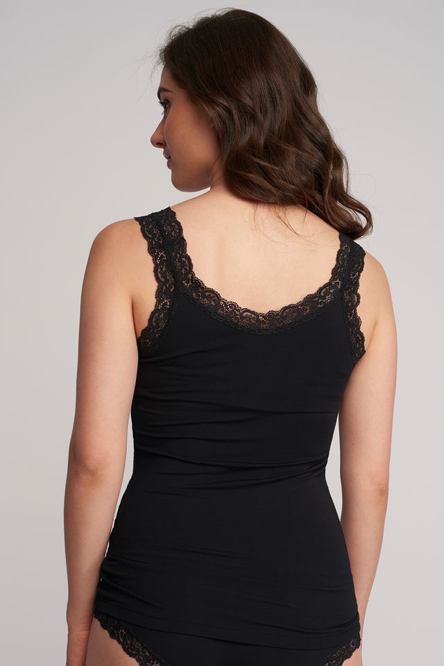 Black lace-trimmed dress worn by a model on a plain background
