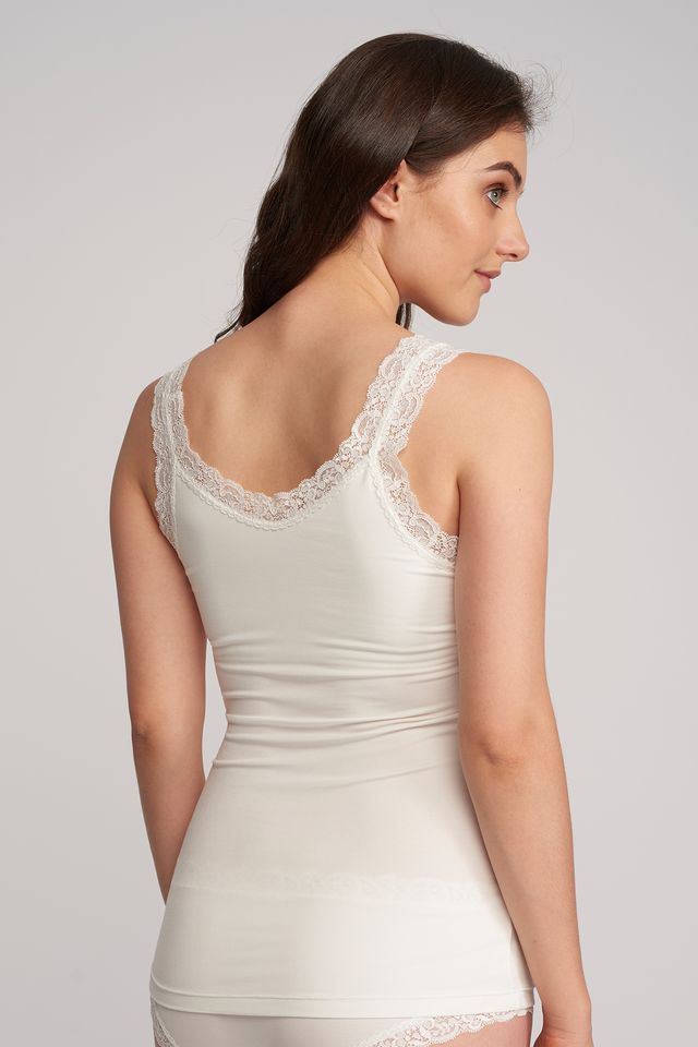 Woman wearing a white lace-trimmed nightgown against a plain background
