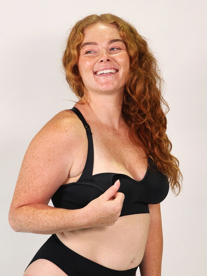 Woman wearing a black bra and underwear set against a plain background
