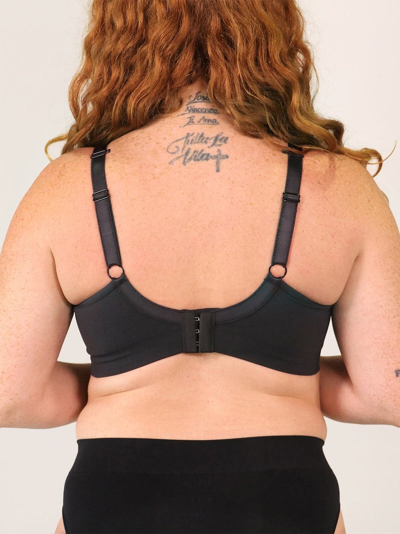 Person wearing a black bra against a plain background